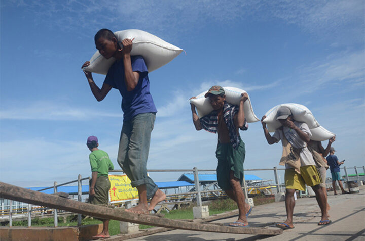 Photo shows Workers carrying bags of rice at the Botahtaung Jetty in Yangon .  NS